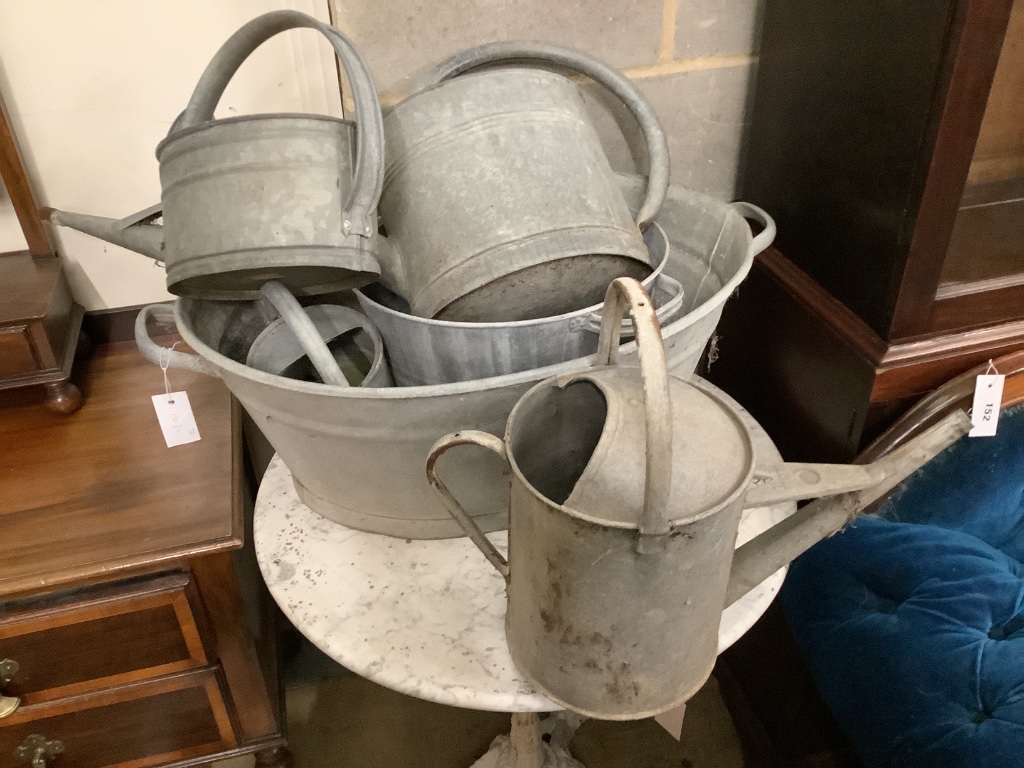 Two galvanised tubs, larger width 80cm, together with four watering cans